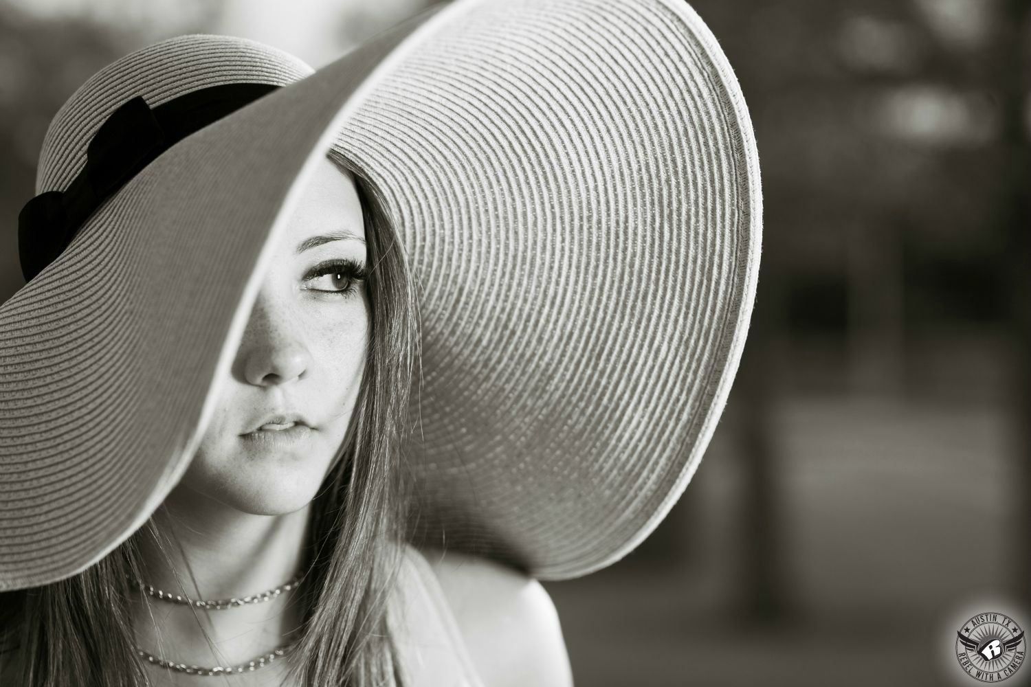 fashion model with sandy colored hair with a large floppy hat looking off into the distance in black and white